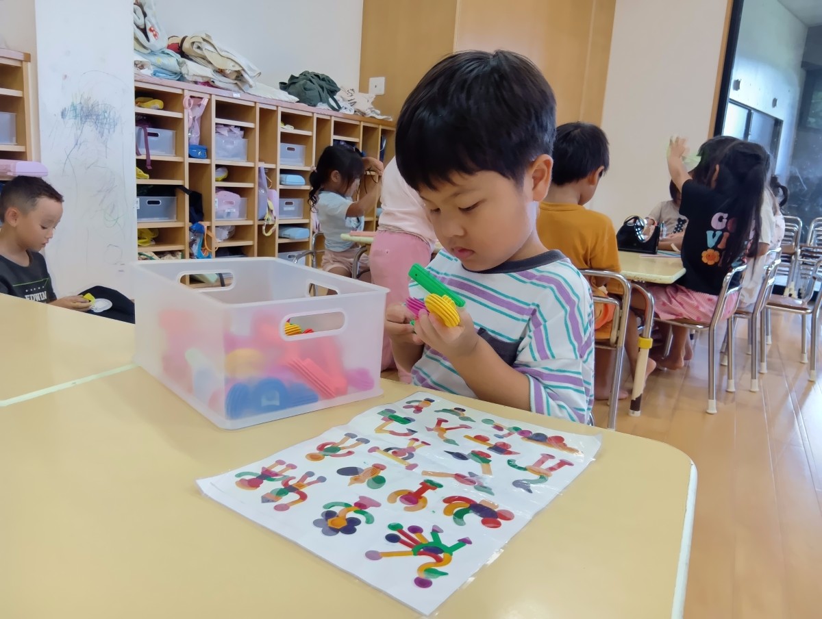 先程と同じ子どもが左手でブロックを支え、右の指先を使ってブロックに触れている