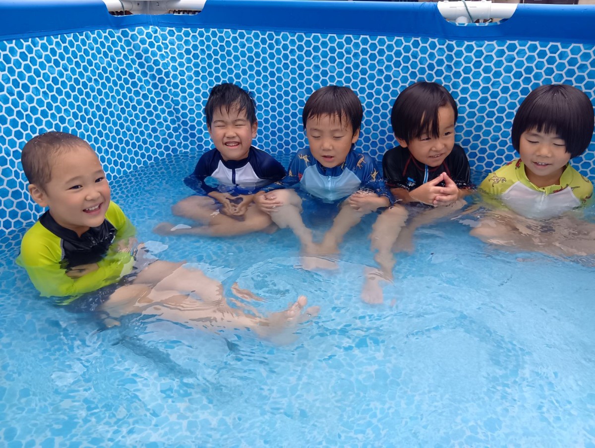 プールの端に集まった子どもたちは、座禅を組んだり、プールの床に座って笑ったりしている