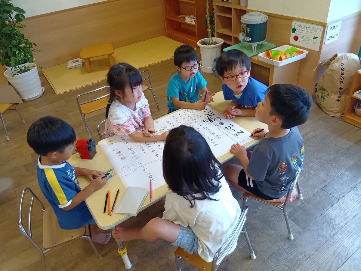 「ボーリングのルール」が書かれた模造紙が置いてある一つの机に、6人の子どもたちが集まる話し合いをしている