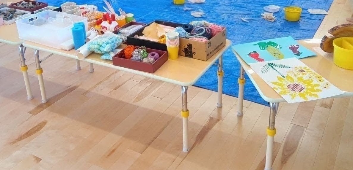 机の上には毛糸やストロー、廃材や石や切り株、ボンド、手本などが置かれている