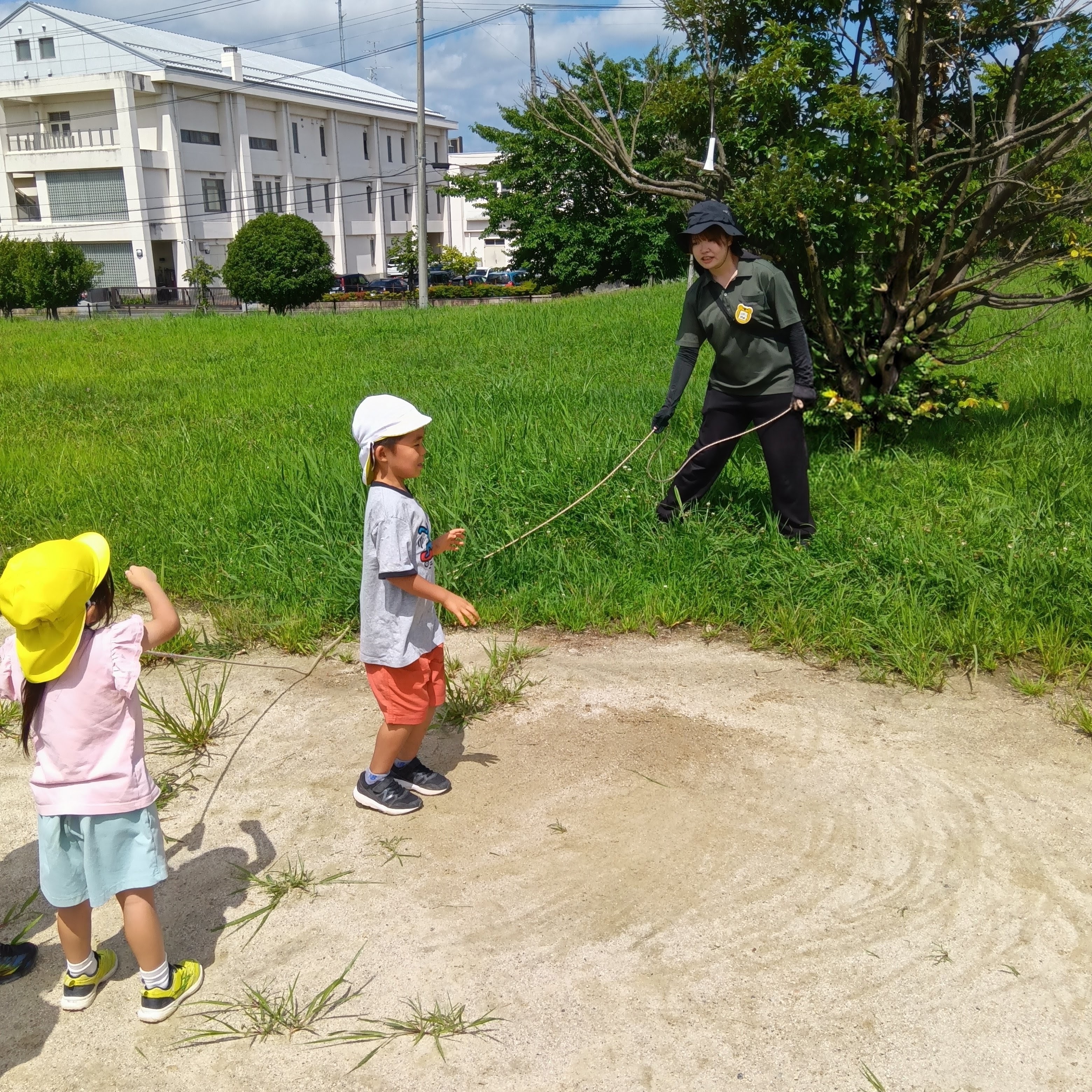 戸外では、大人が大繩を回し、子どもたちは順番に跳んでいる