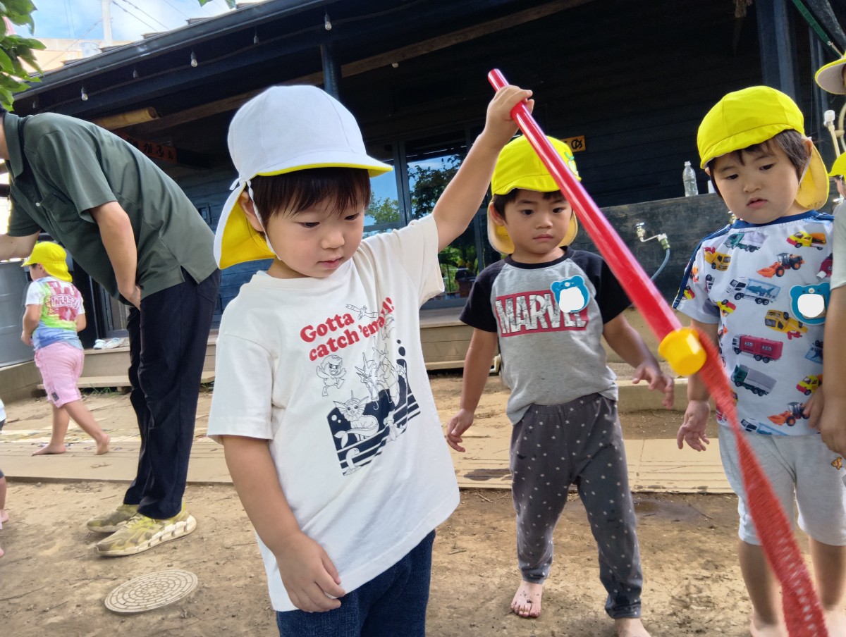 一人の子どもが赤い棒を持って、棒の先を見つめている