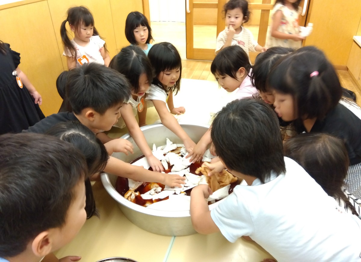 子どもたちは染液に布を浸し込んでいる