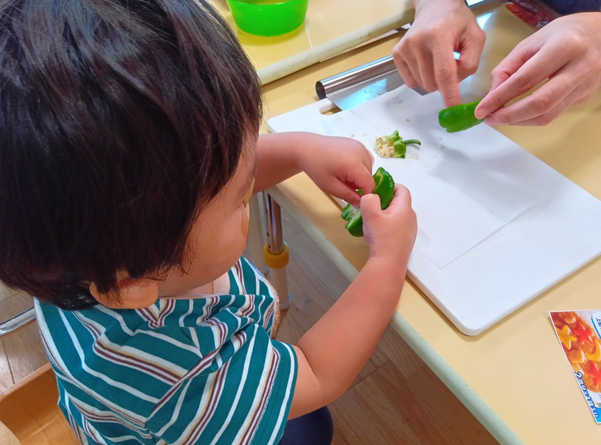 一人の子どもが半分に切られたピーマンの種を指を使って取り除いている