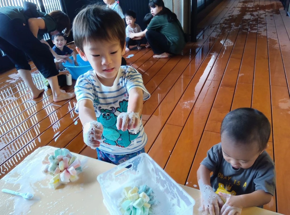 机の上にはスポンジと半透明ボックスが泡だらけになって置かれており、子どもたちは両手を泡だらけにしている