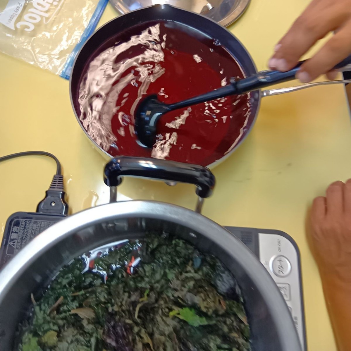鍋には紫色の液体が入っており、一人の大人がお玉で液体を混ぜている