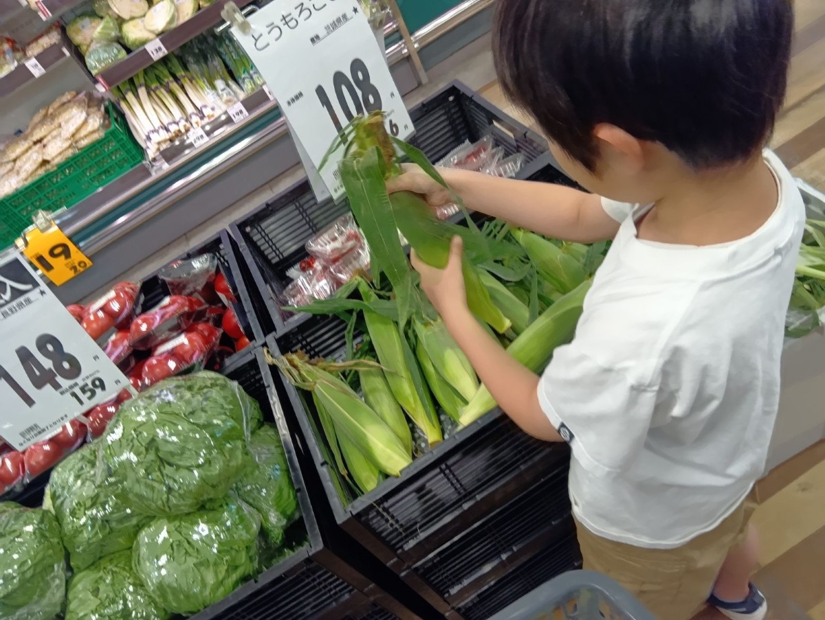 店内では、一人の子どもがトウモロコシを手に取っている