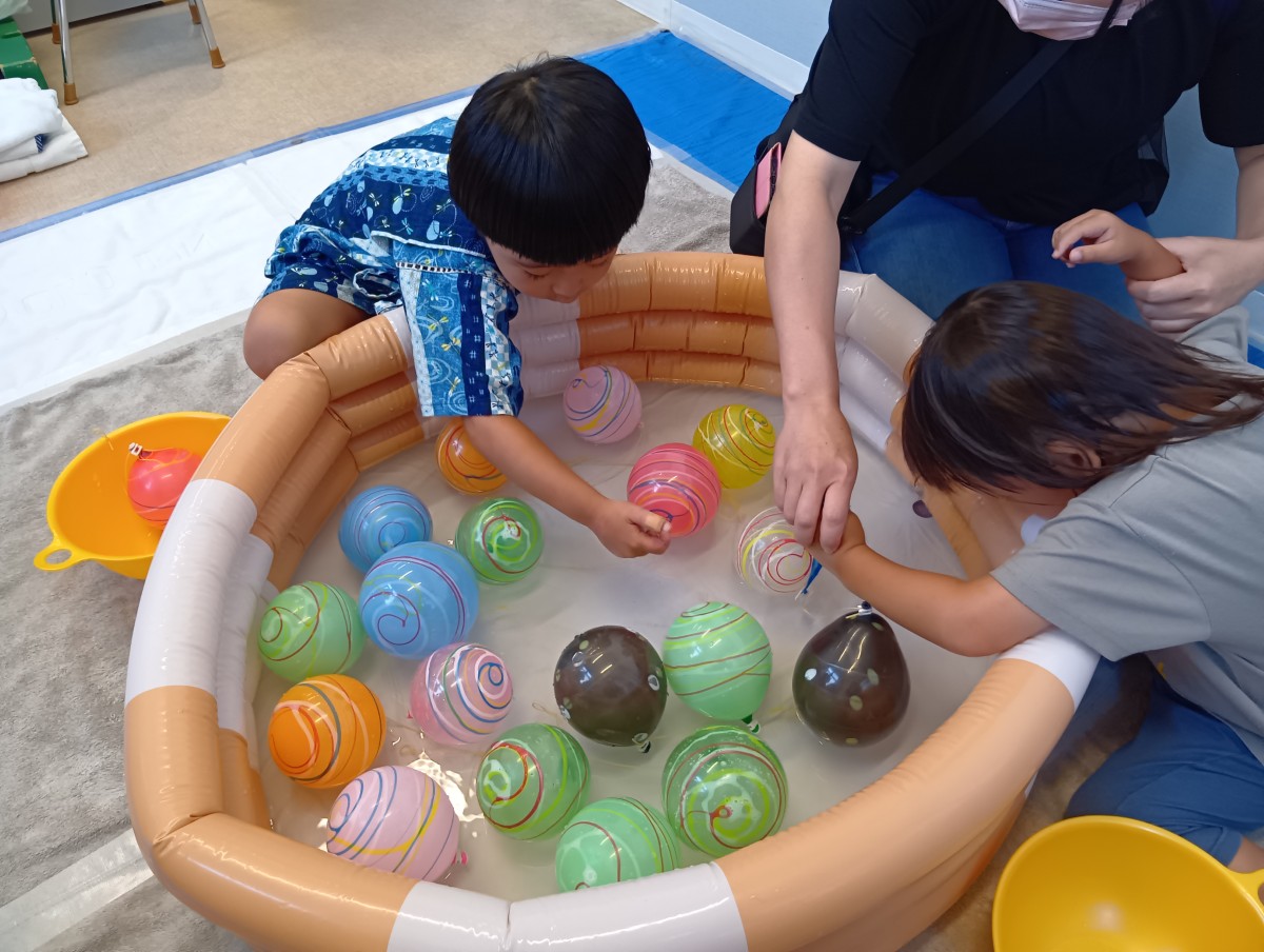 ヨーヨーのコーナーでは、大人と子どもがヨーヨー釣りをしている