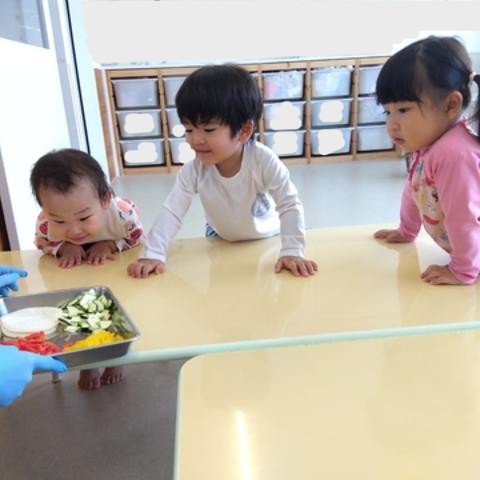 子どもたちは、ピザにのせる切られた野菜を体を乗り出して覗き込んでいる