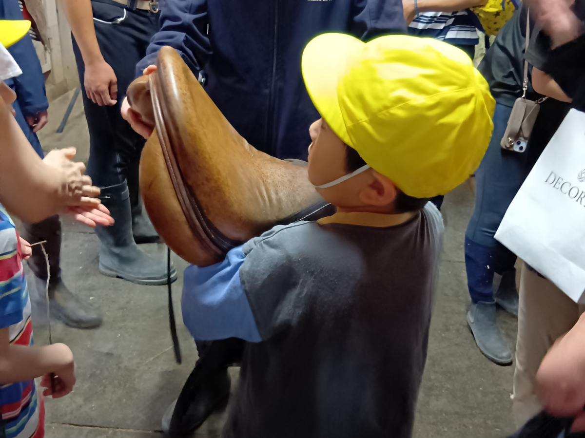 鞍を持ち上げる子ども