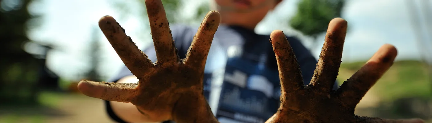 A child holding muddy hands up to the camera