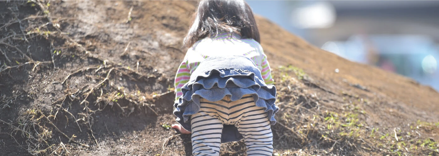 A child climbing a mound of earth