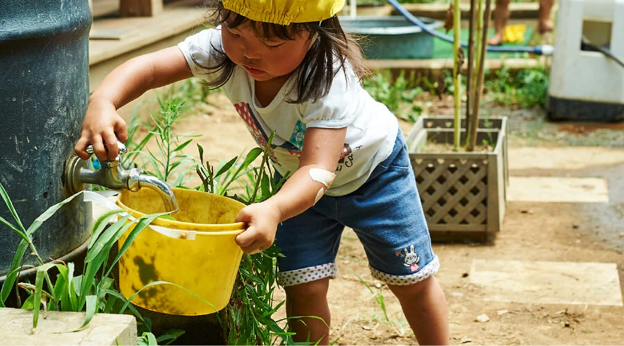 A child filling a bucket with water