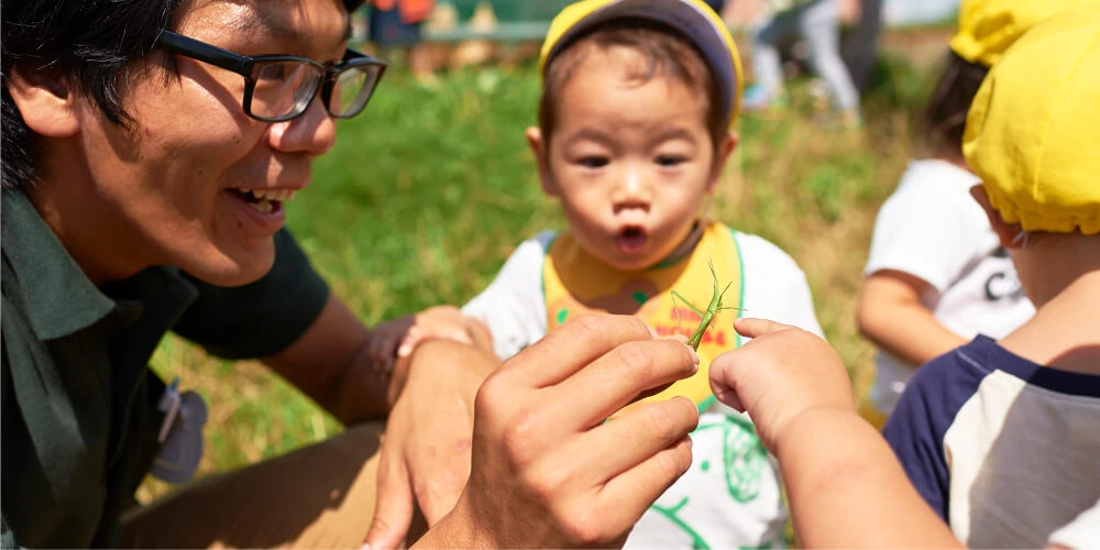 A staff member observing grass with children