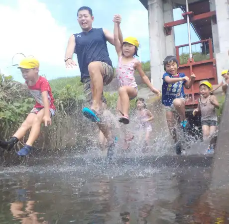 Children and a staff member playing in a puddle