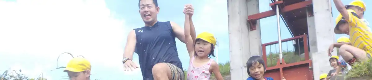 A staff member holding hands with children outdoors