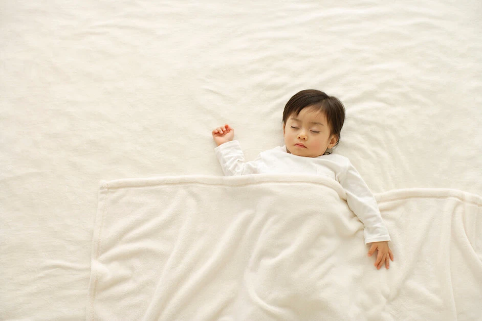 白い寝具で眠る子ども