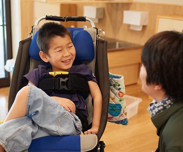 A staff member talking with a child using a wheelchair