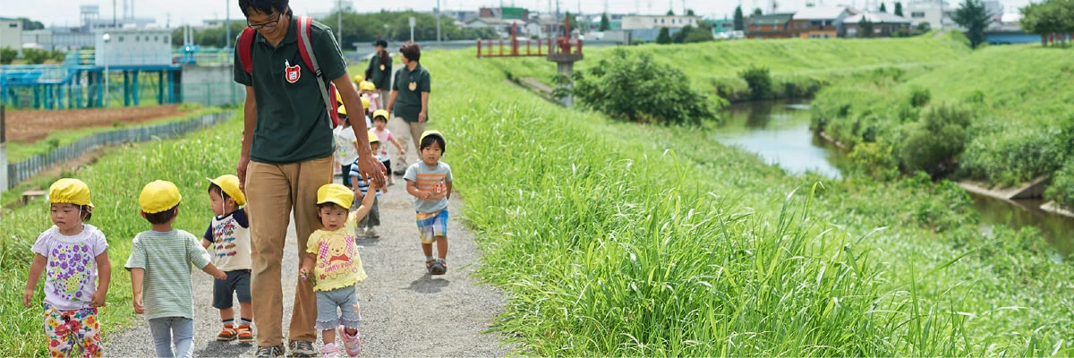 A staff member walking along a riverside with children