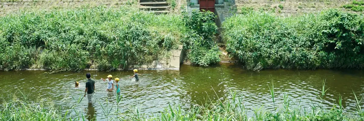 Children playing in a stream with a staff member
