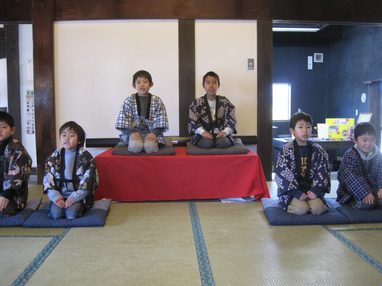 Children wearing happi coats seated in a tatami room