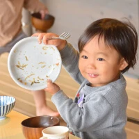 A child smiling while holding an empty plate after lunch