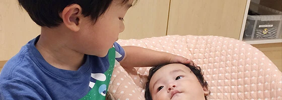 An older child gently touching a baby