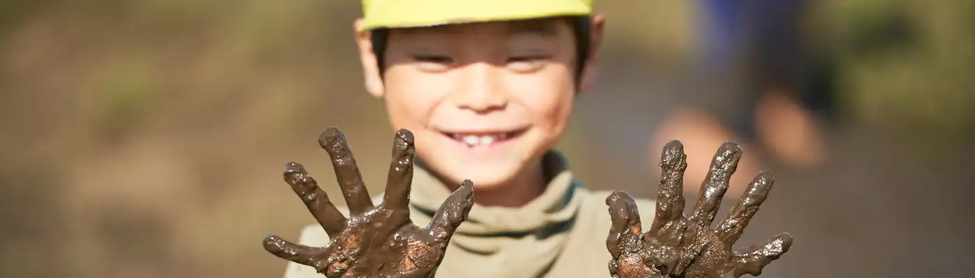 泥だらけの手を見せる子ども