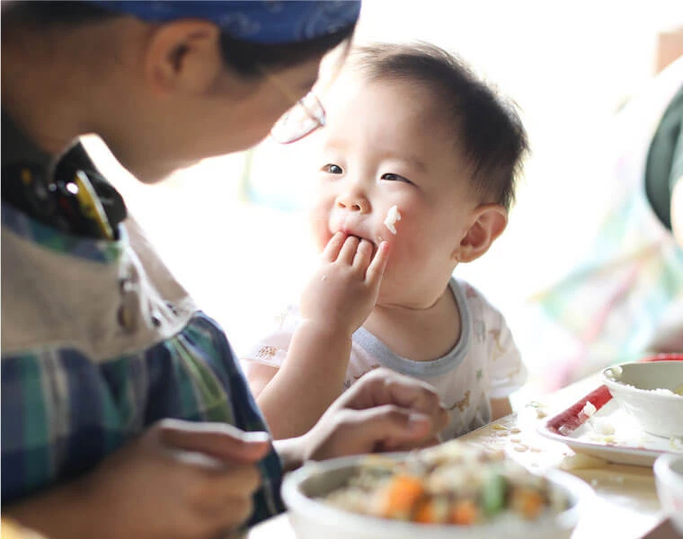 A child eating a meal with an adult