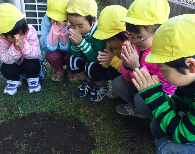 Children gathered on the ground with their hands together