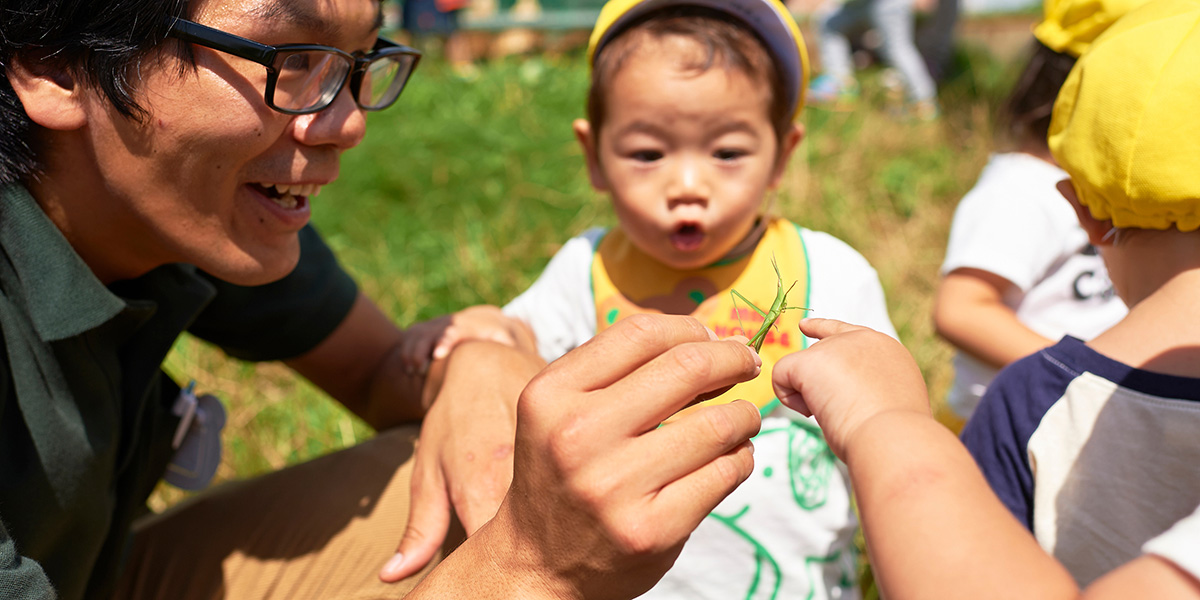 スタッフと子どもたちがバッタを観察する様子
