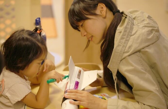 学生とペットボトルに色付けする園児