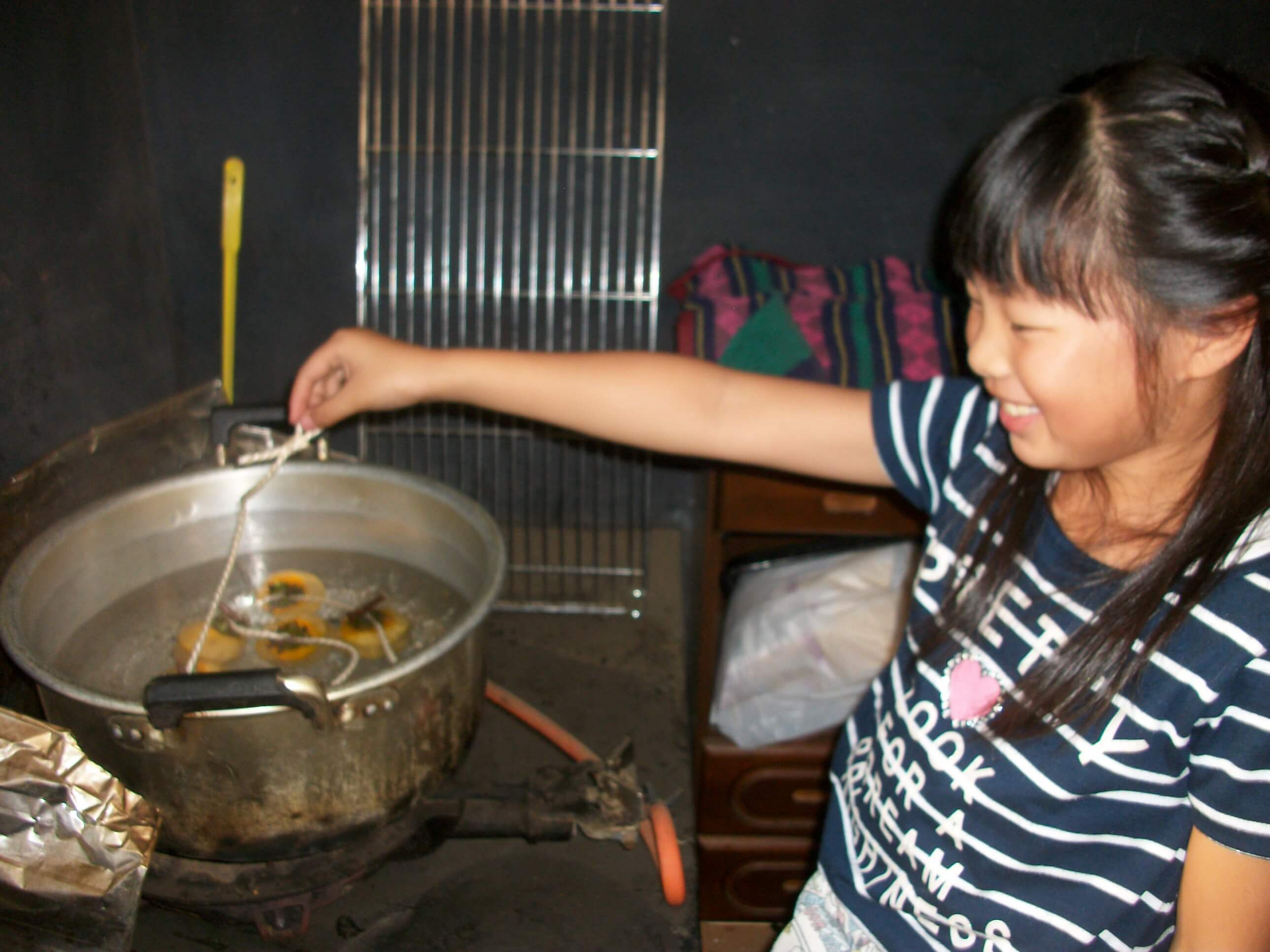 干し柿用に柿を煮沸する子ども