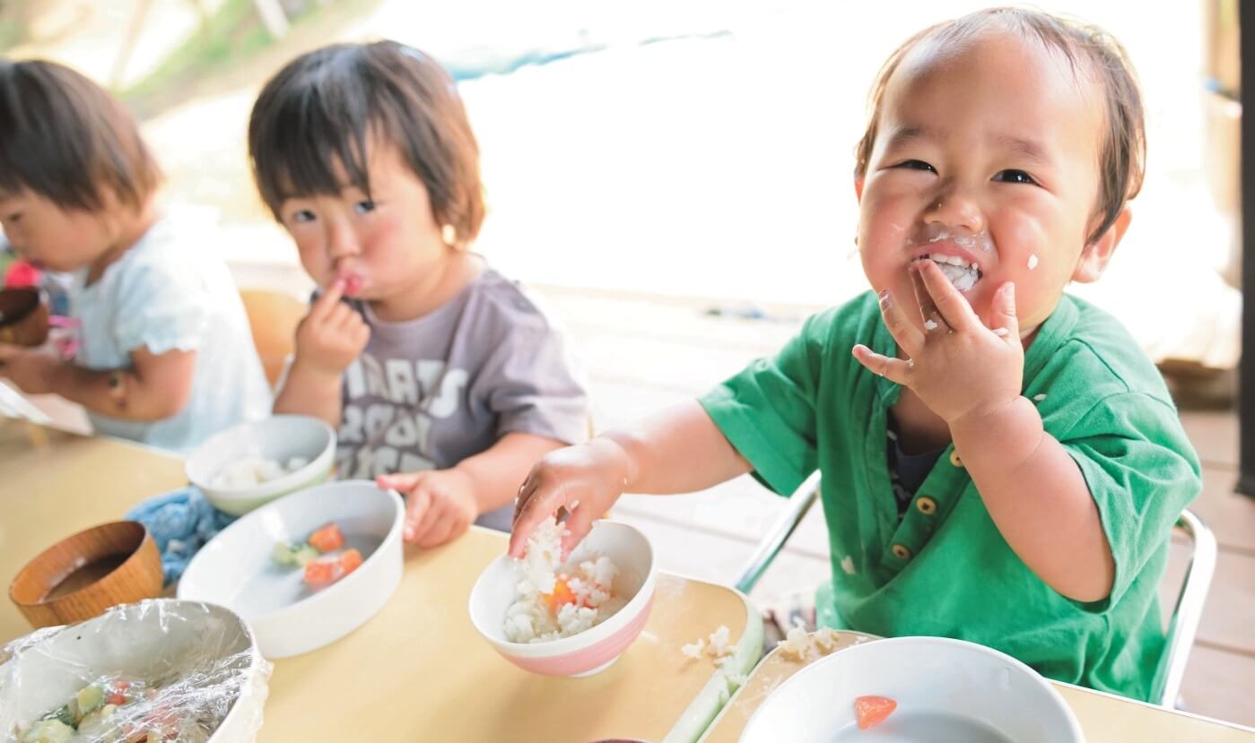 手づかみで給食を食べる子どもたち