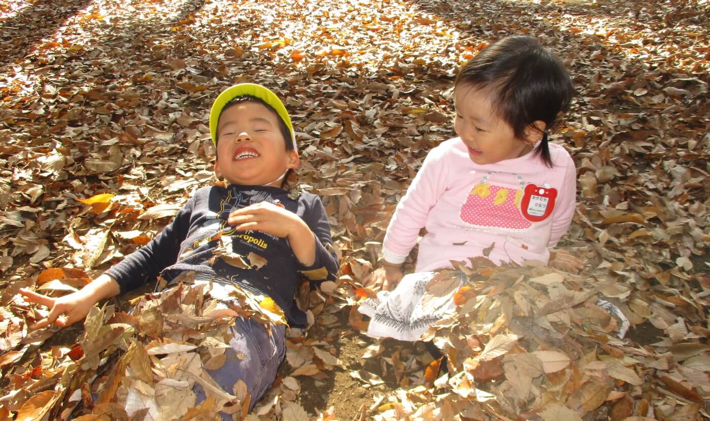 落ち葉で遊ぶ子ども
