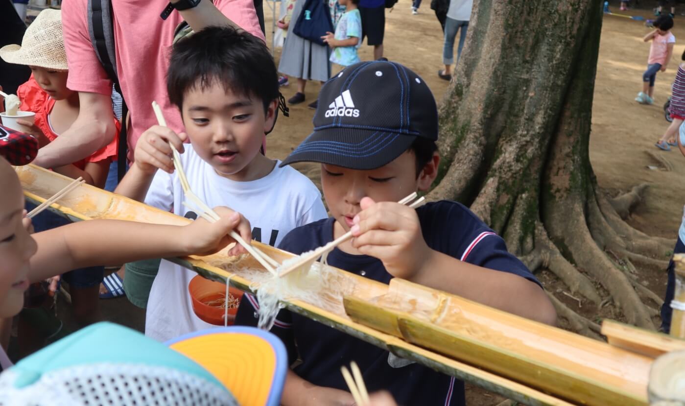 流しそうめんを食べる男の子