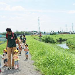 川沿いを散歩する園児と保育士たち