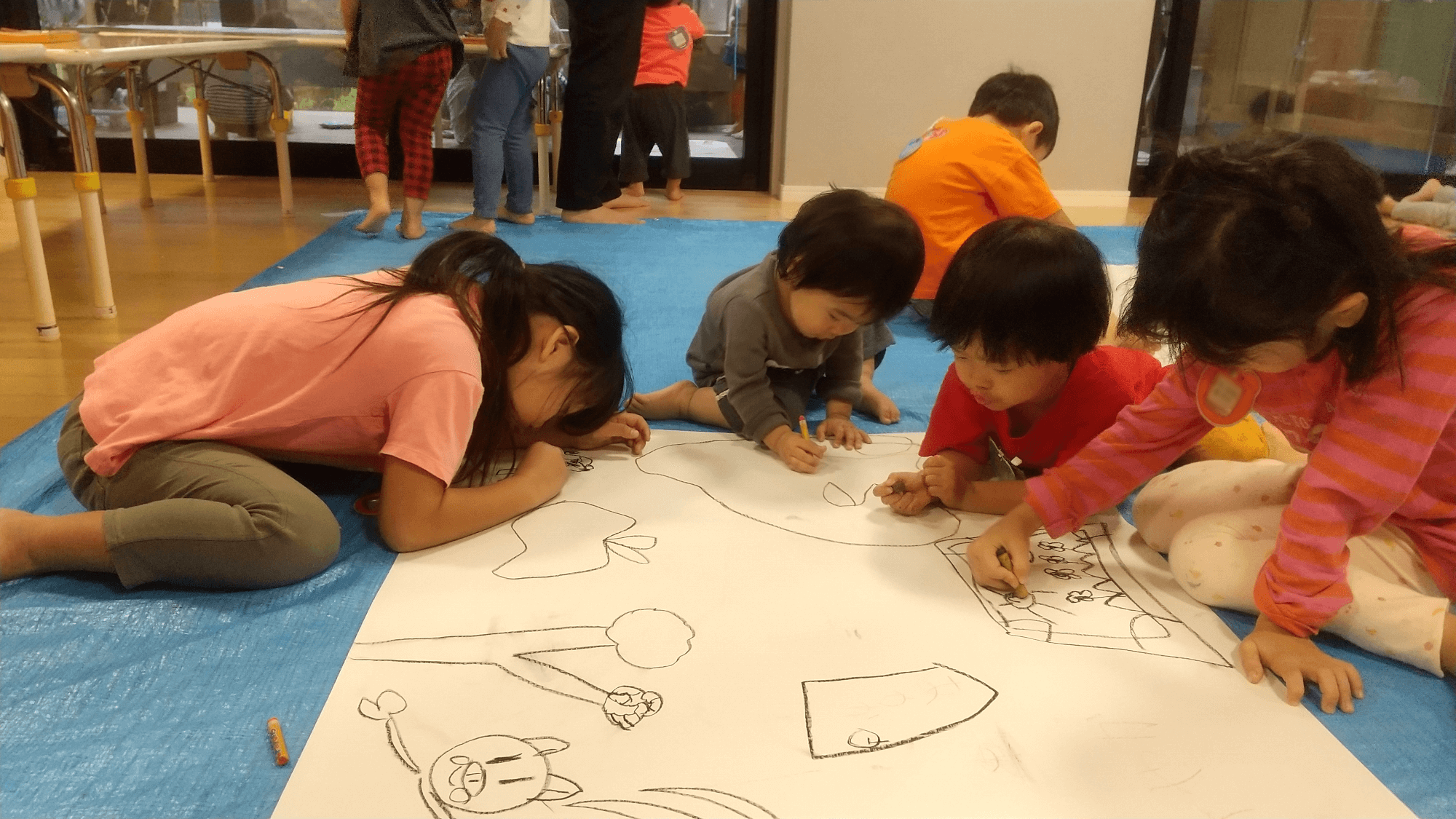 大きな模造紙に絵を描く子どもたち