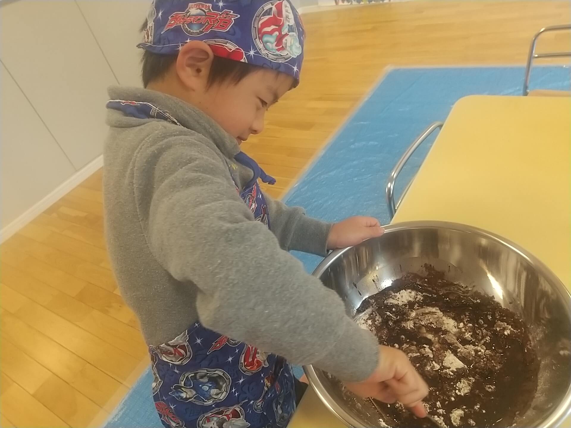 大きなボウルでクッキーの材料を混ぜる子ども