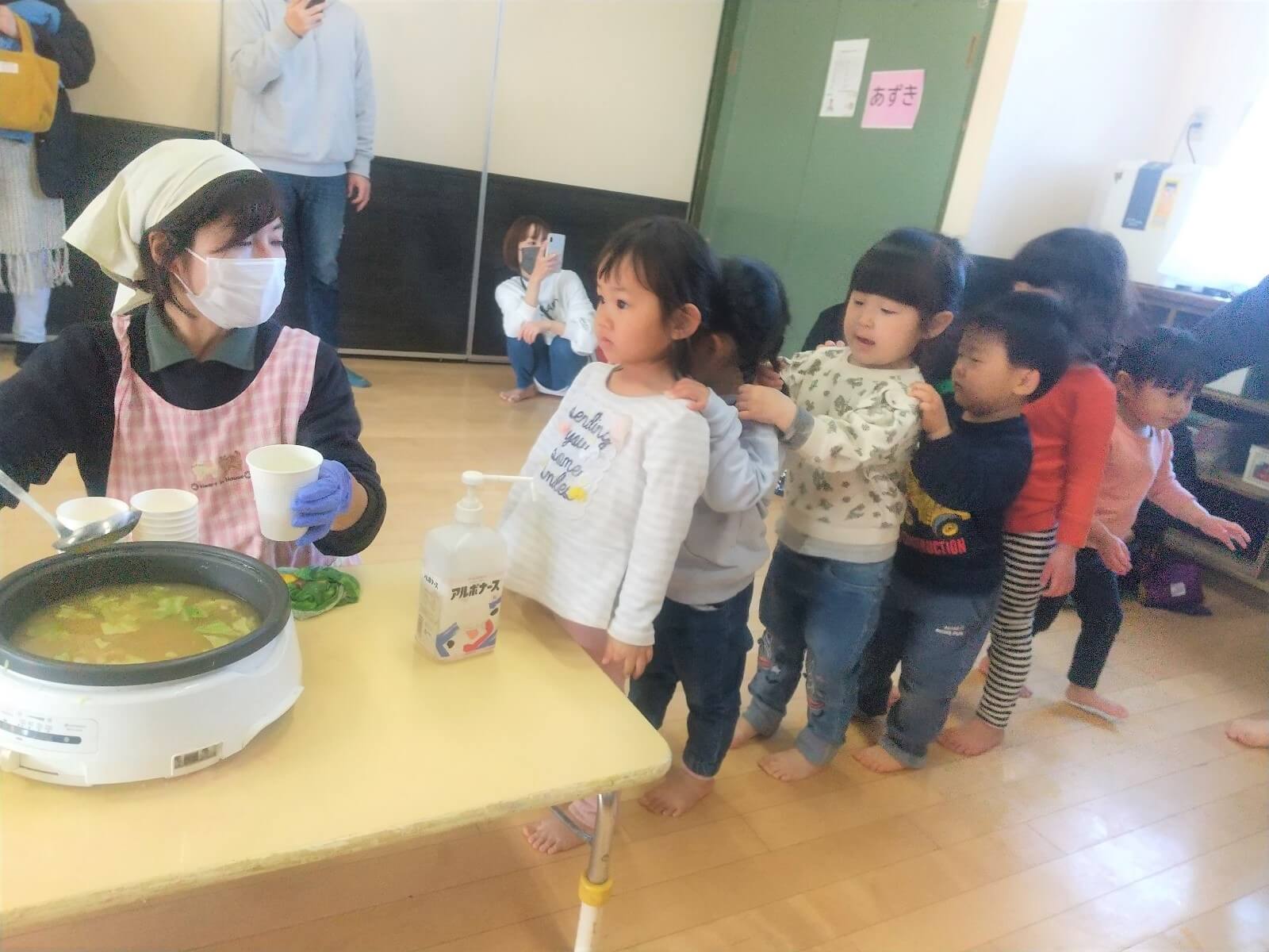 みそ汁の配膳に並ぶ子どもたち