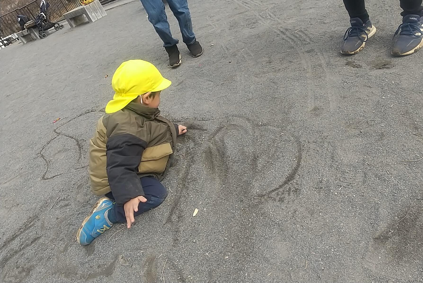 砂の上に絵を描く子ども