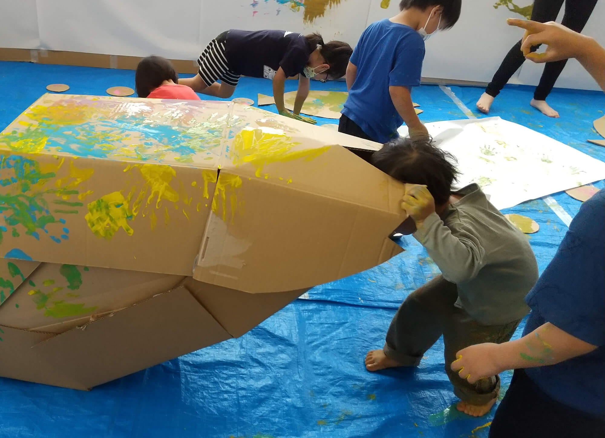 段ボールで作った魚の口の中をのぞく子ども