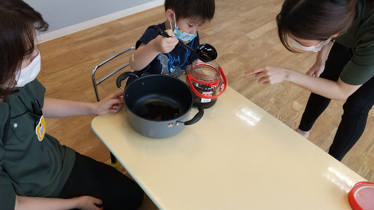 梅シロップを鍋に移す子ども