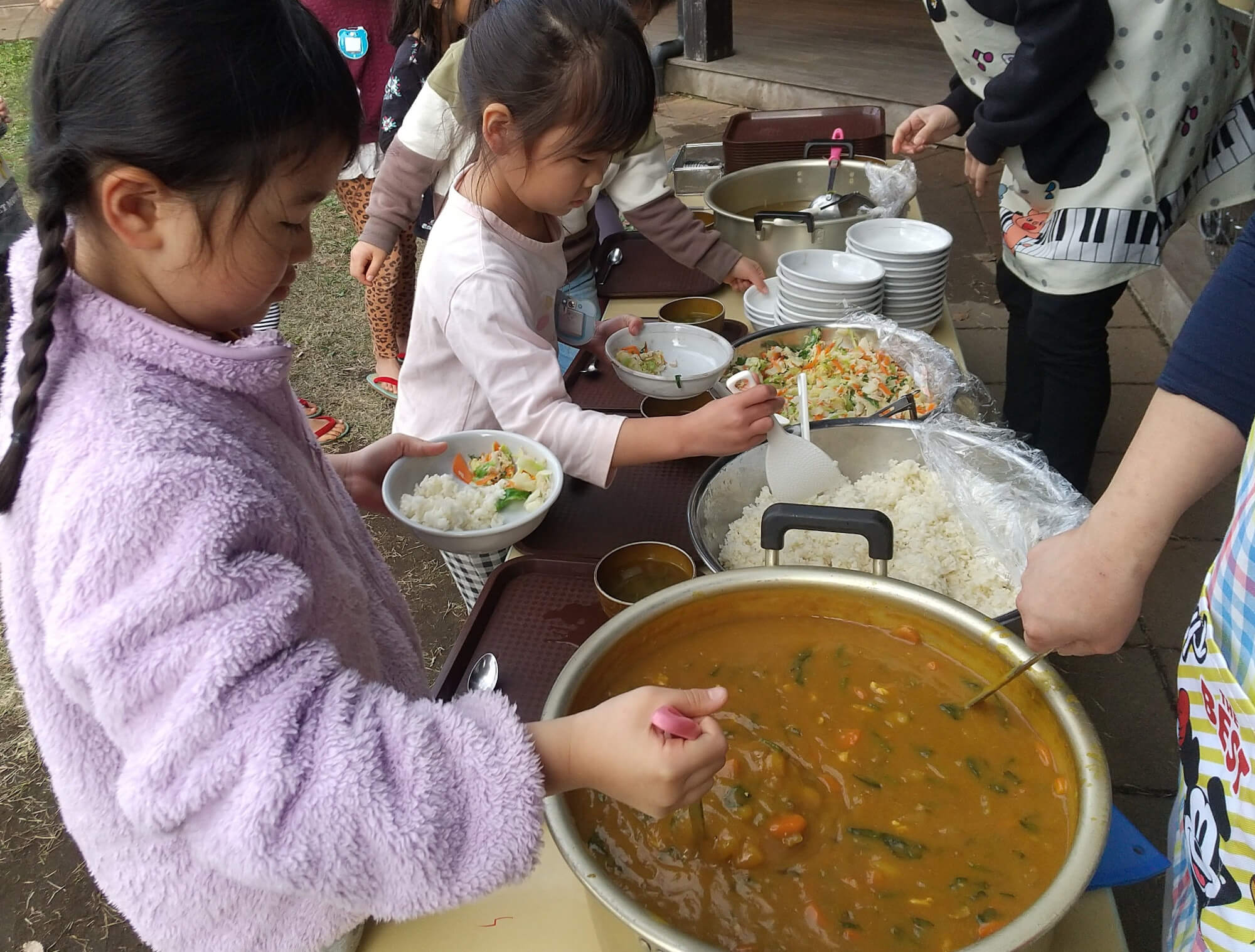 外でカレーを食べる準備をする子どもたち