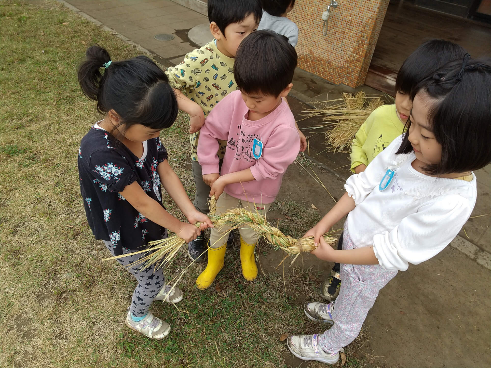 土俵の囲いをしめ縄で作る子どもたち