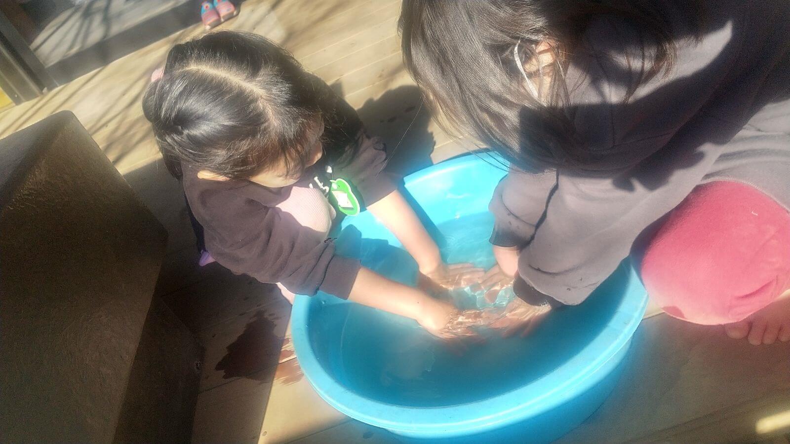 タライのお湯で手を温める子どもたち