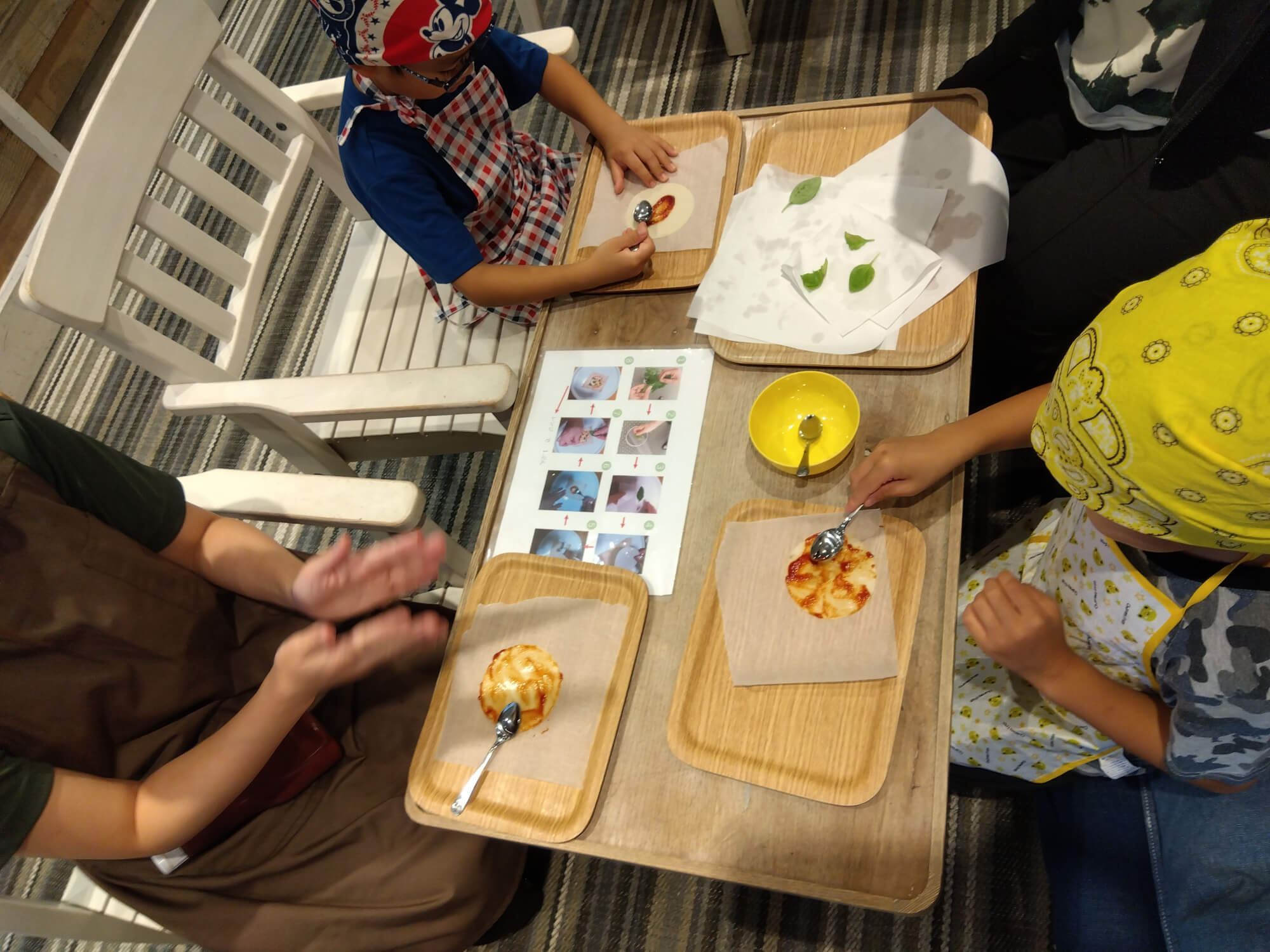 レシピを見ながらピザ作りをする子どもたち