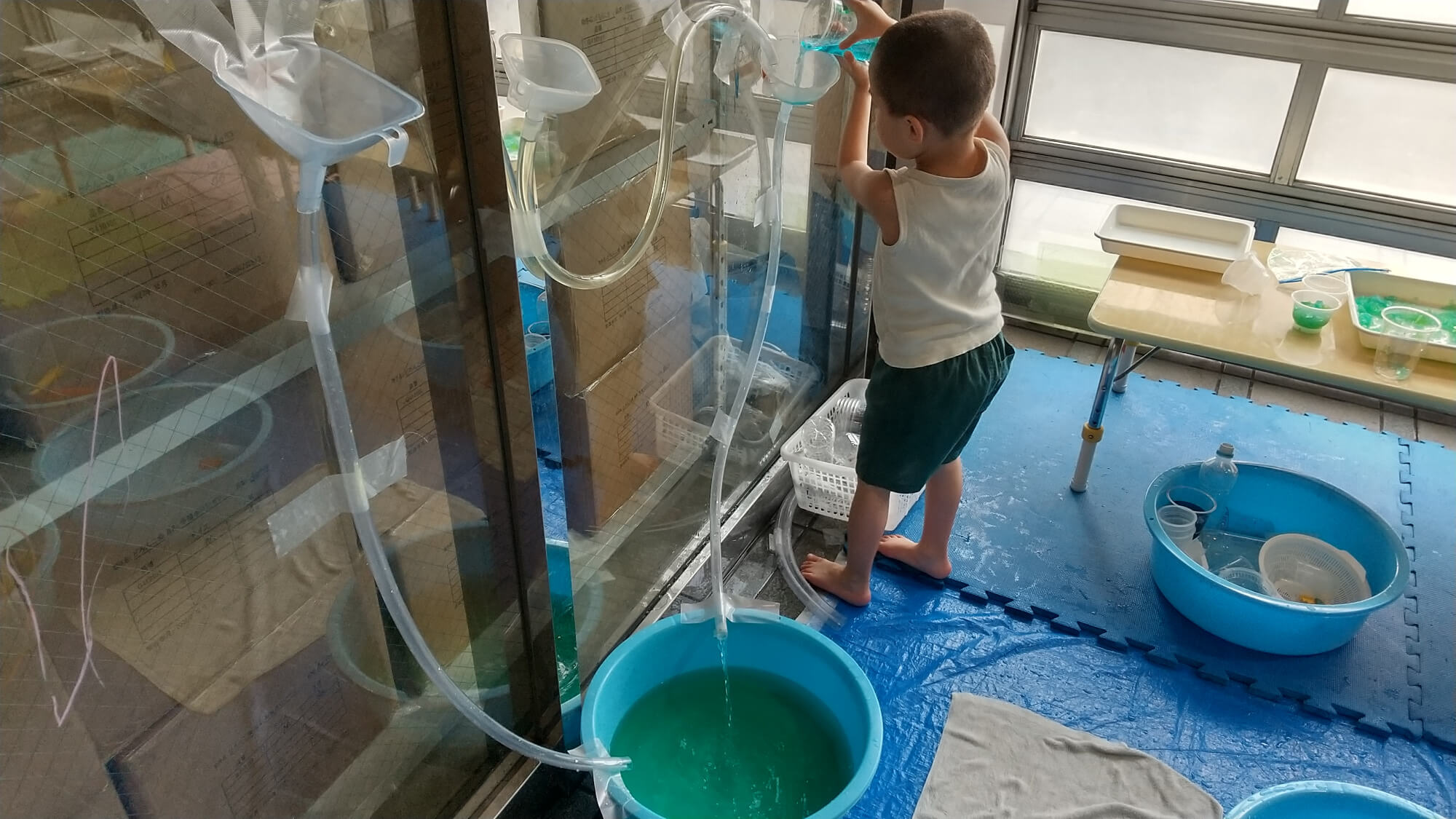 じょうごに色水を入れる子ども