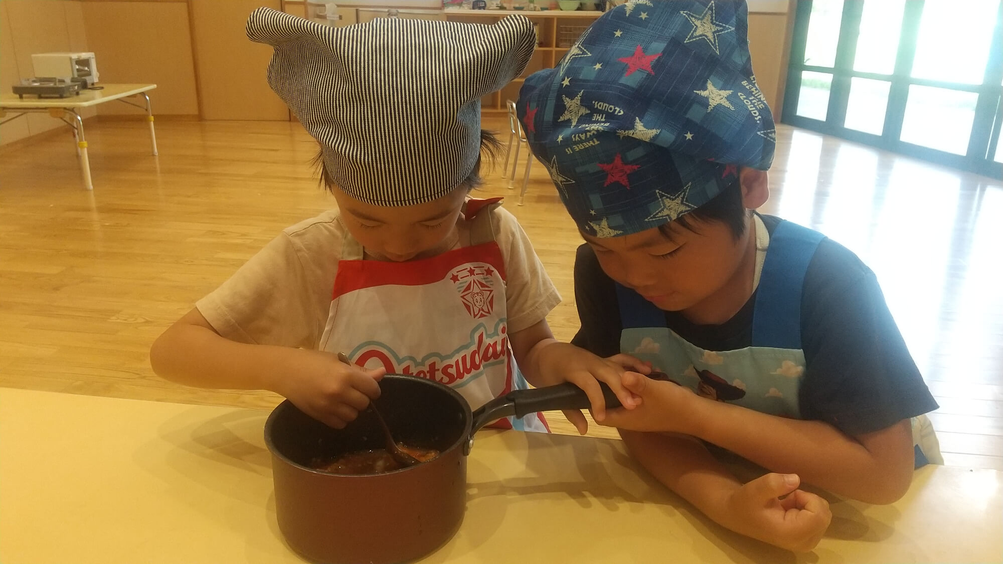 鍋を混ぜる子どもと支える子ども
