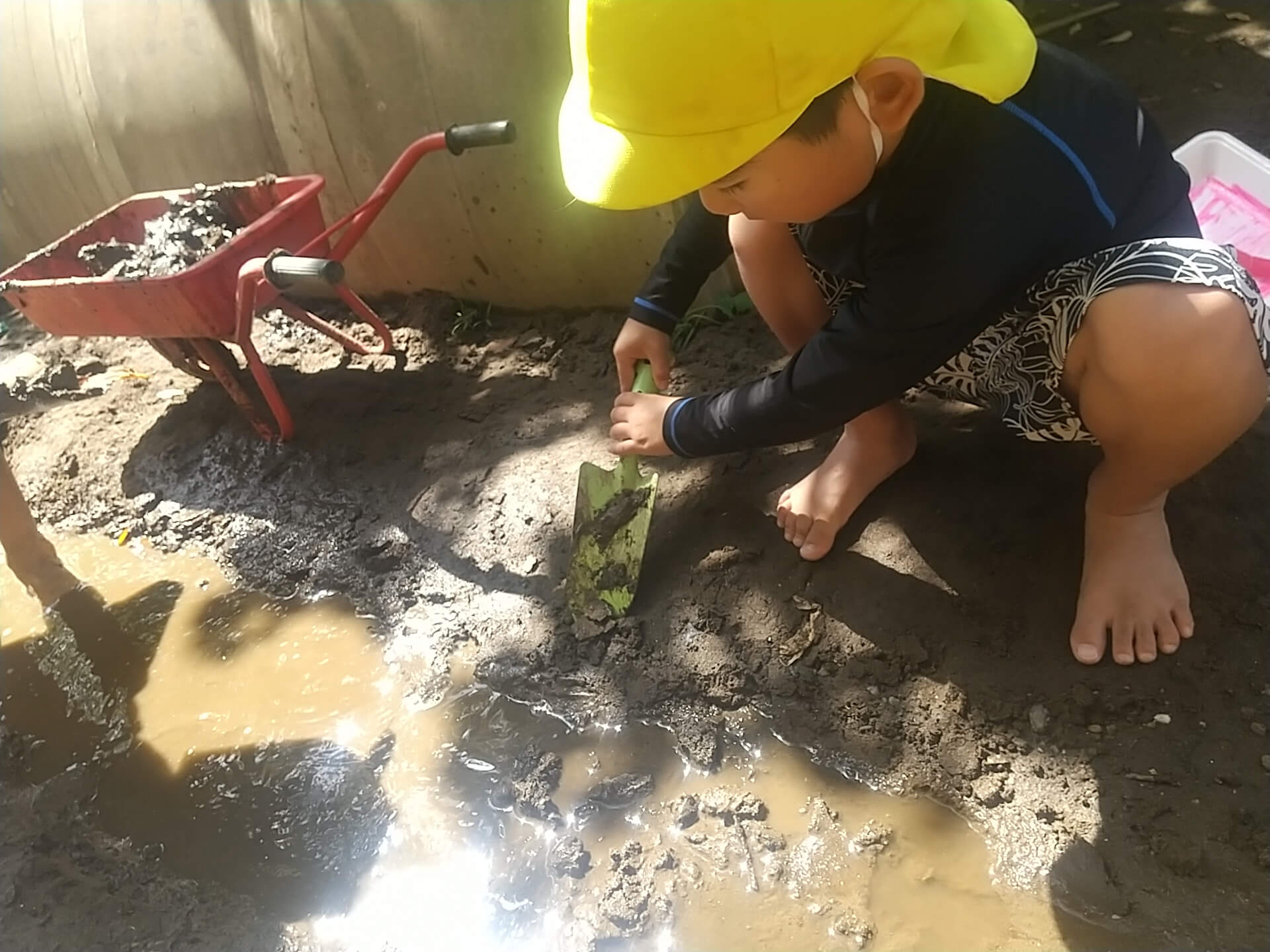 シャベルで泥を掘る子ども